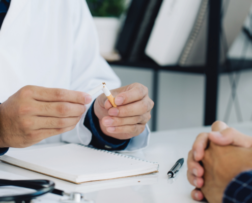 Ein Arzt zeigt einem Patienten, wie eine Zigarette zerbrochen wird, um auf die Gefahren des Rauchens hinzuweisen.