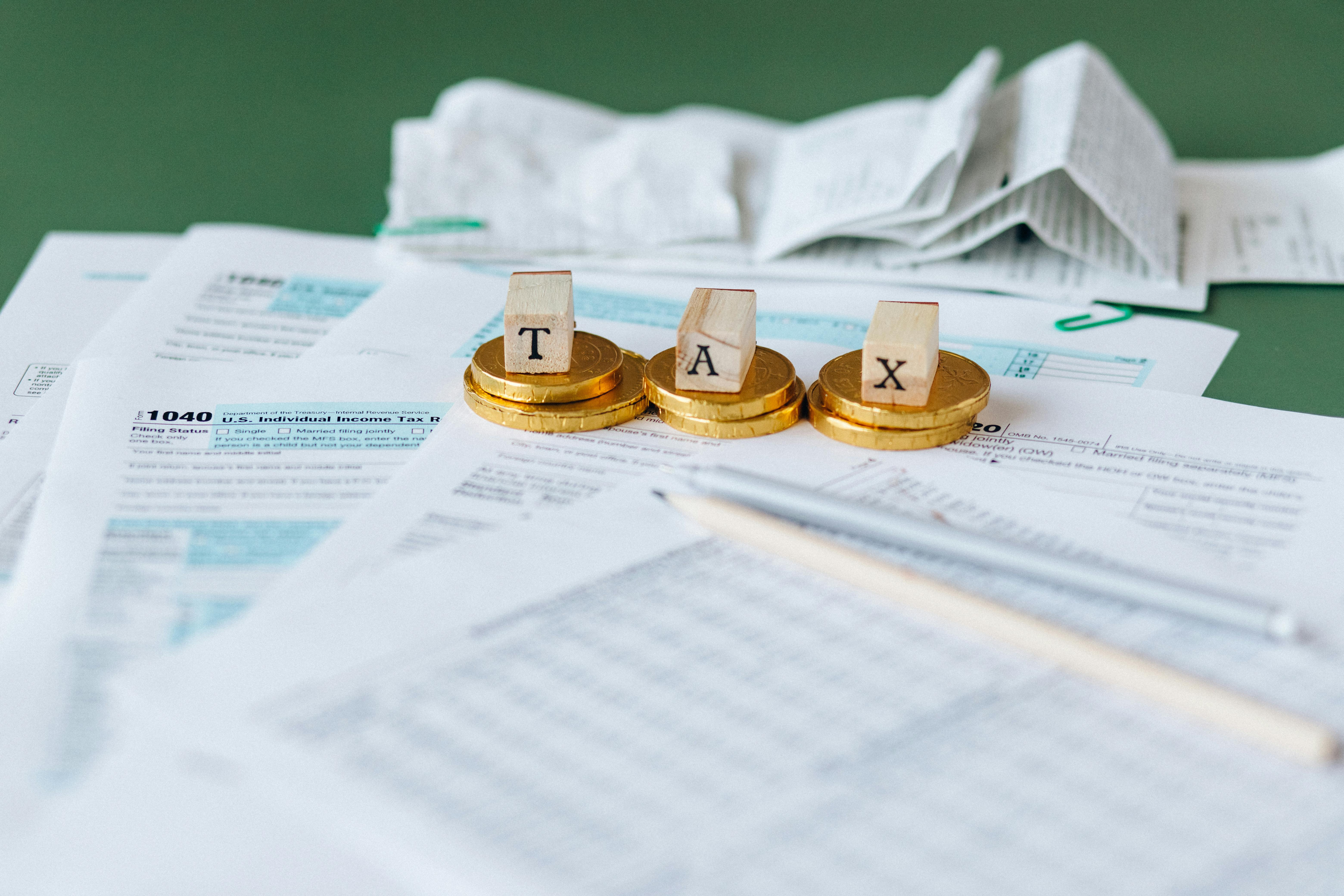 TAX geschrieben auf Holzblöcken mit Steuerdokumenten