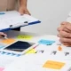 Zwei Personen arbeiten an einem Tisch mit Notizen, Diagrammen und einem Tablet.