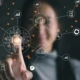 Person berührt digitales Interface mit Netzwerksymbolen und Datenvisualisierungen.